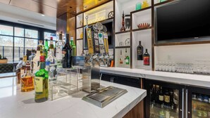 A bar area with a variety of liquor bottles, a tap system, and a television screen. - Cambria Hotel Arundel Mills - BWI Airport (Hanover)
