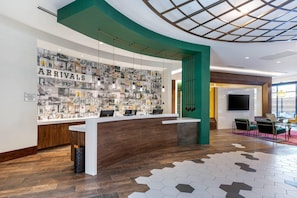 Área de recepção de hotel com uma parede de cartazes de viagens, um balcão de madeira e design de interiores moderno.