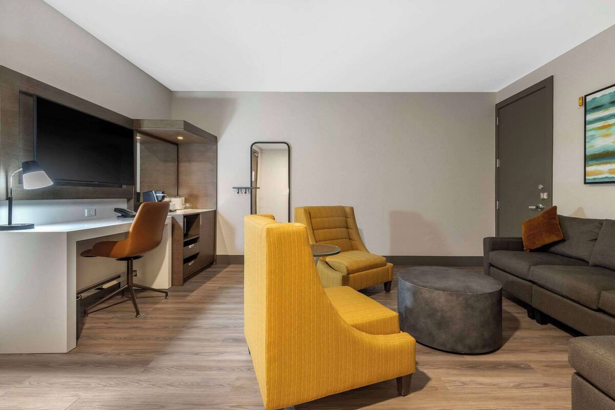 A modern living room with a sofa, armchairs, a coffee table, and a desk with a chair.