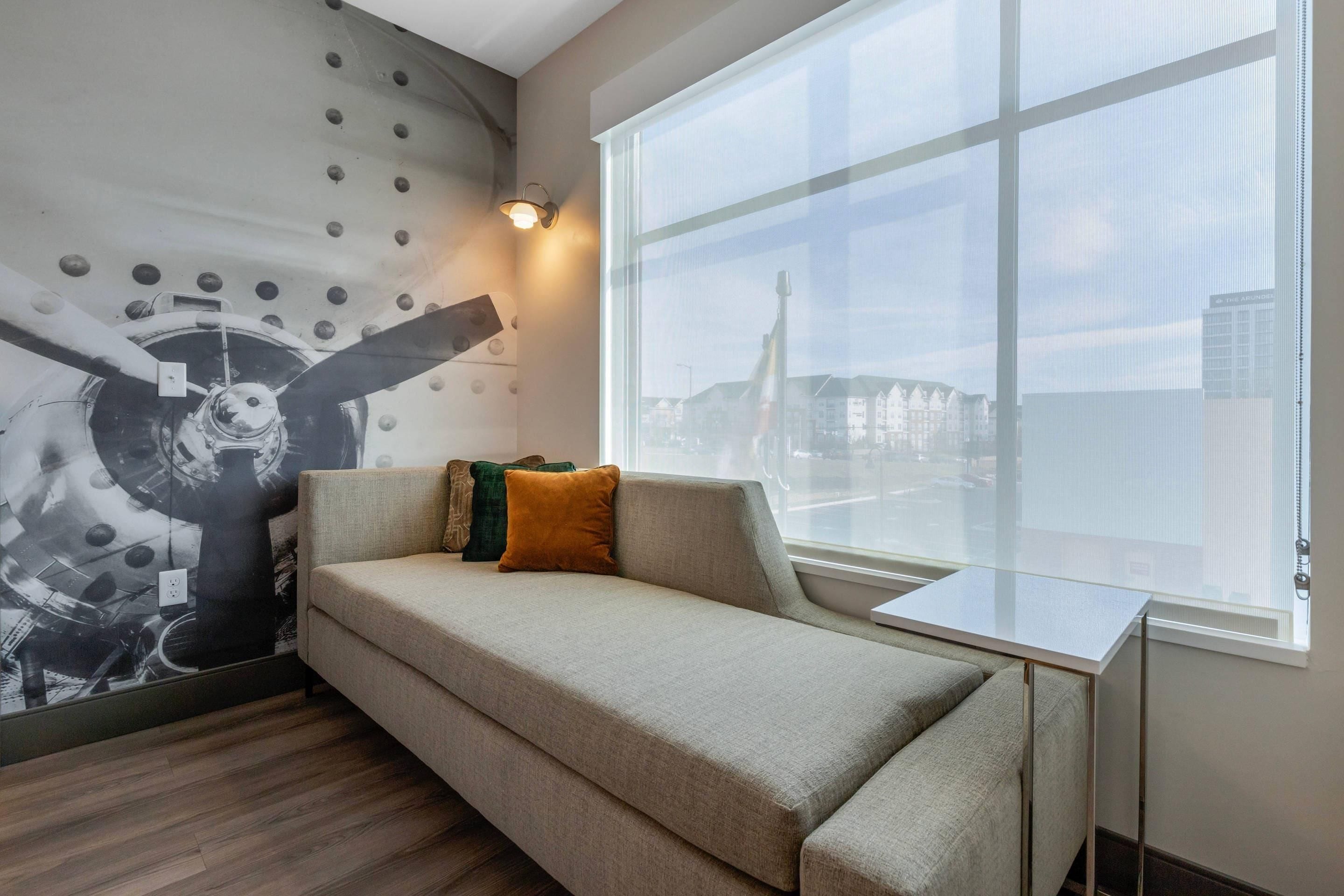 Un salon moderne avec un canapé, une grande fenêtre et une fresque murale.