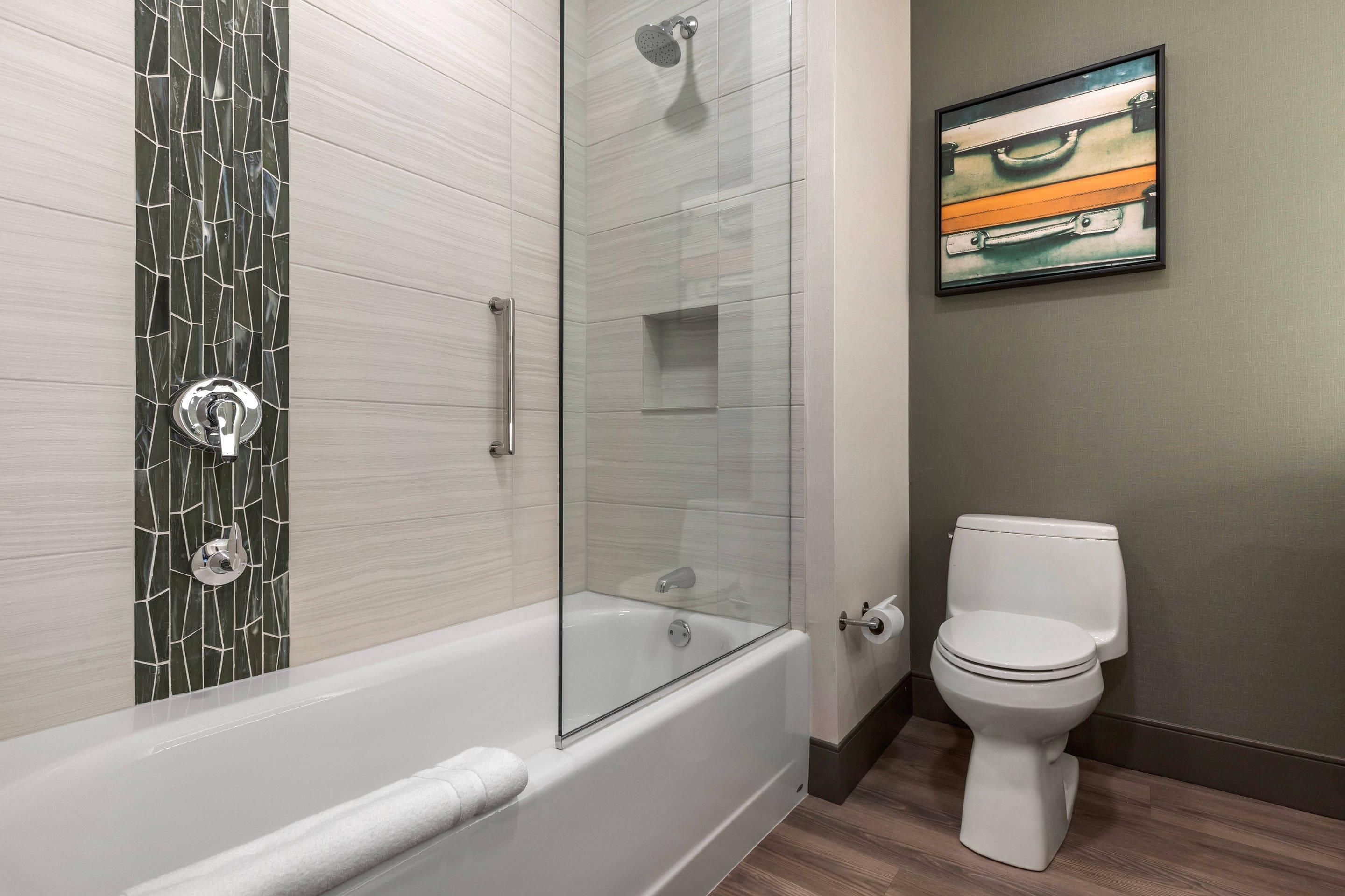 A bathroom with a glass-enclosed shower, a white toilet, and a framed picture on the wall.