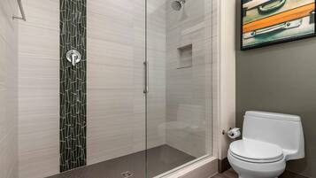 Une salle de bain moderne avec une douche à parois de verre, des toilettes et un tableau encadré au mur.