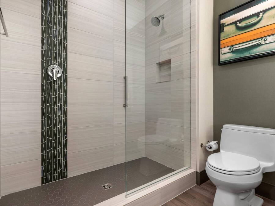 Une salle de bain moderne avec une douche à parois de verre, des toilettes et un tableau encadré au mur.