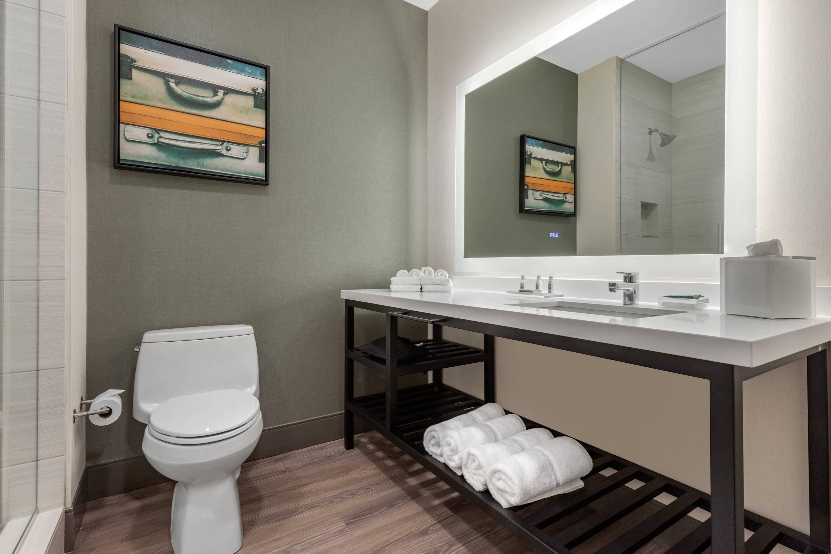 Un baño moderno con inodoro, lavamanos y toallero.