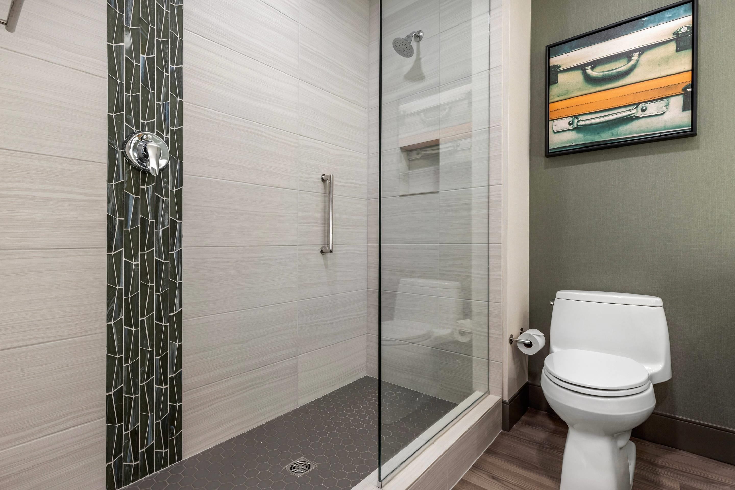 Un baño moderno con cabina de ducha de vidrio, inodoro blanco y lavamanos instalado en la pared.