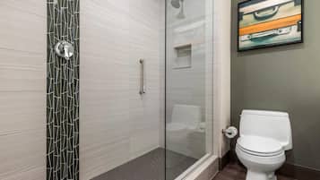 Un bagno moderno con cabina doccia in vetro, un water bianco e un lavandino sospeso.