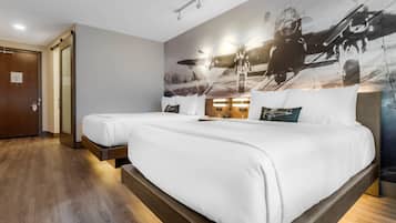 Habitación de hotel con una cama grande, una mesita de noche y una pared con una foto grande.