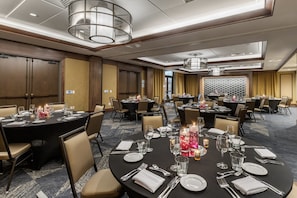 Un salón de conferencias de hotel con mesas redondas dispuestas para comedor, equipado con sillas, mesas y centros de mesa.