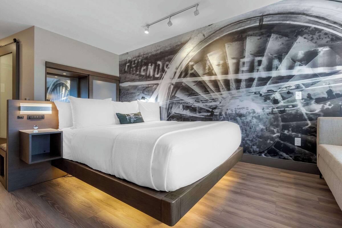 A modern bedroom with a bed, bedside tables, and a large wall mural.