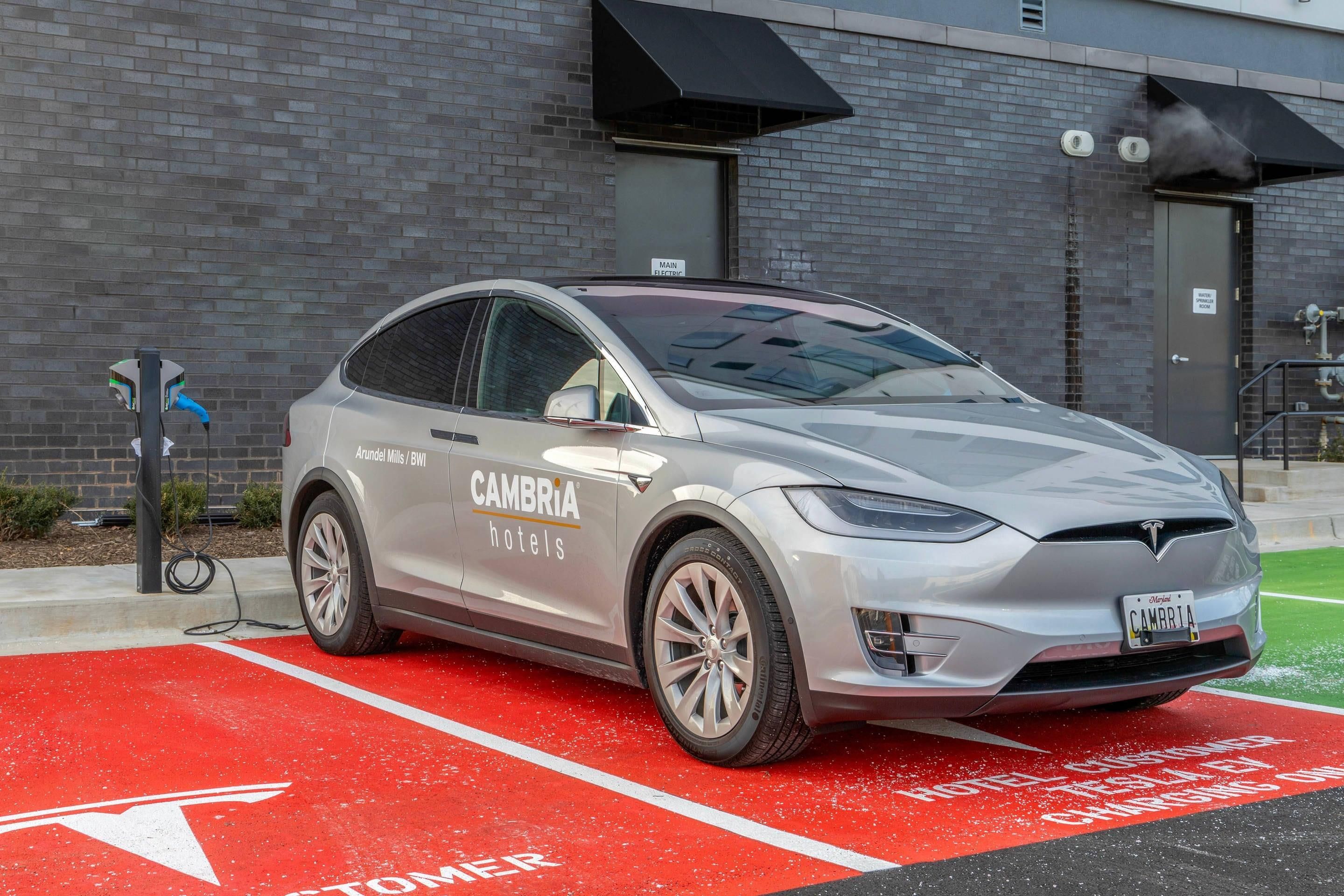 A silver electric vehicle parked in a designated charging spot at a hotel.