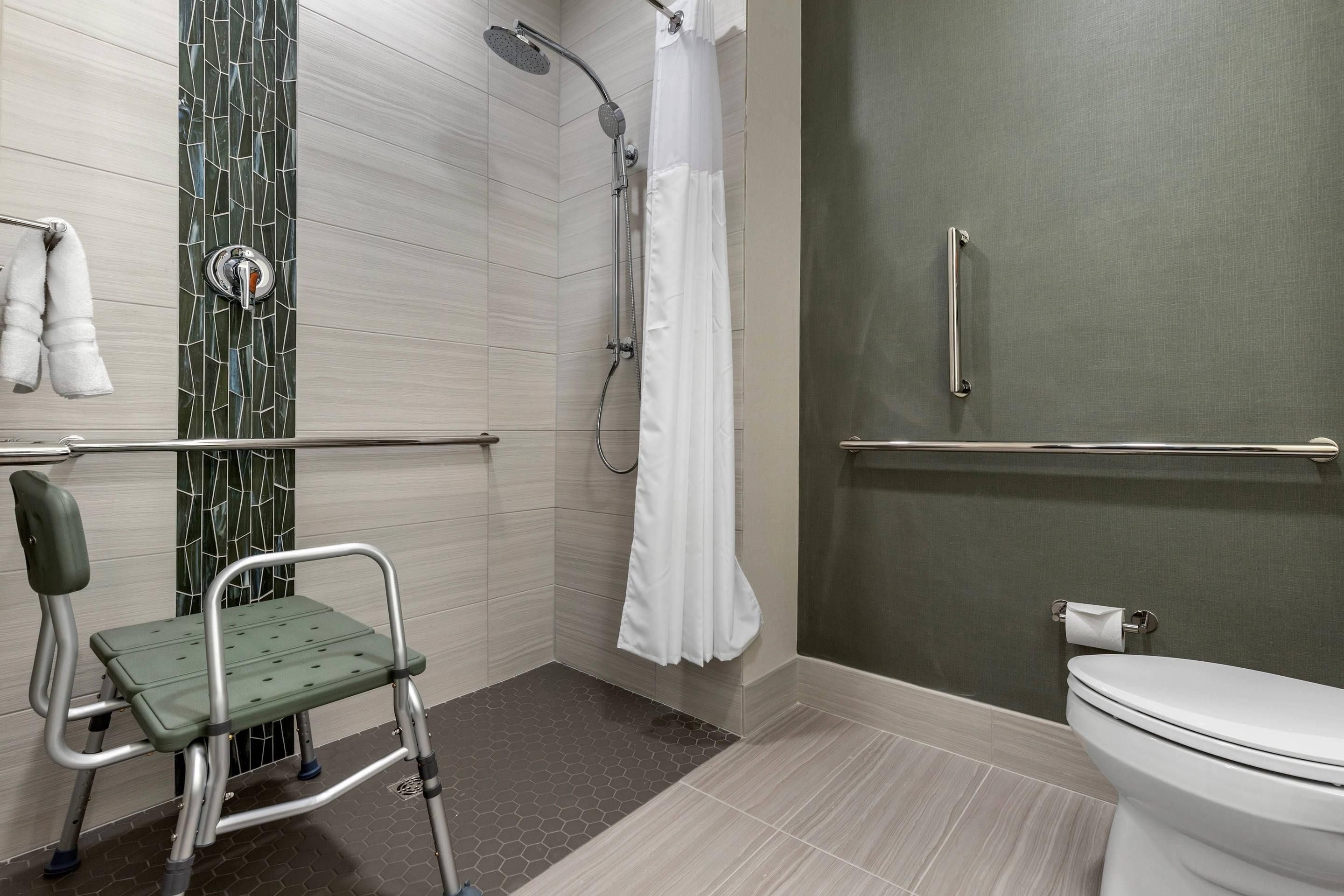 A bathroom with a shower, toilet, and a wheelchair-accessible bench.