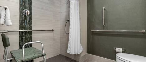A bathroom with a shower, toilet, and a wheelchair-accessible bench.