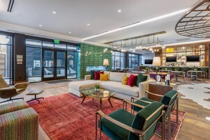 Un moderno vestíbulo de hotel con un área de estar, un bar y una gran pantalla de televisión.