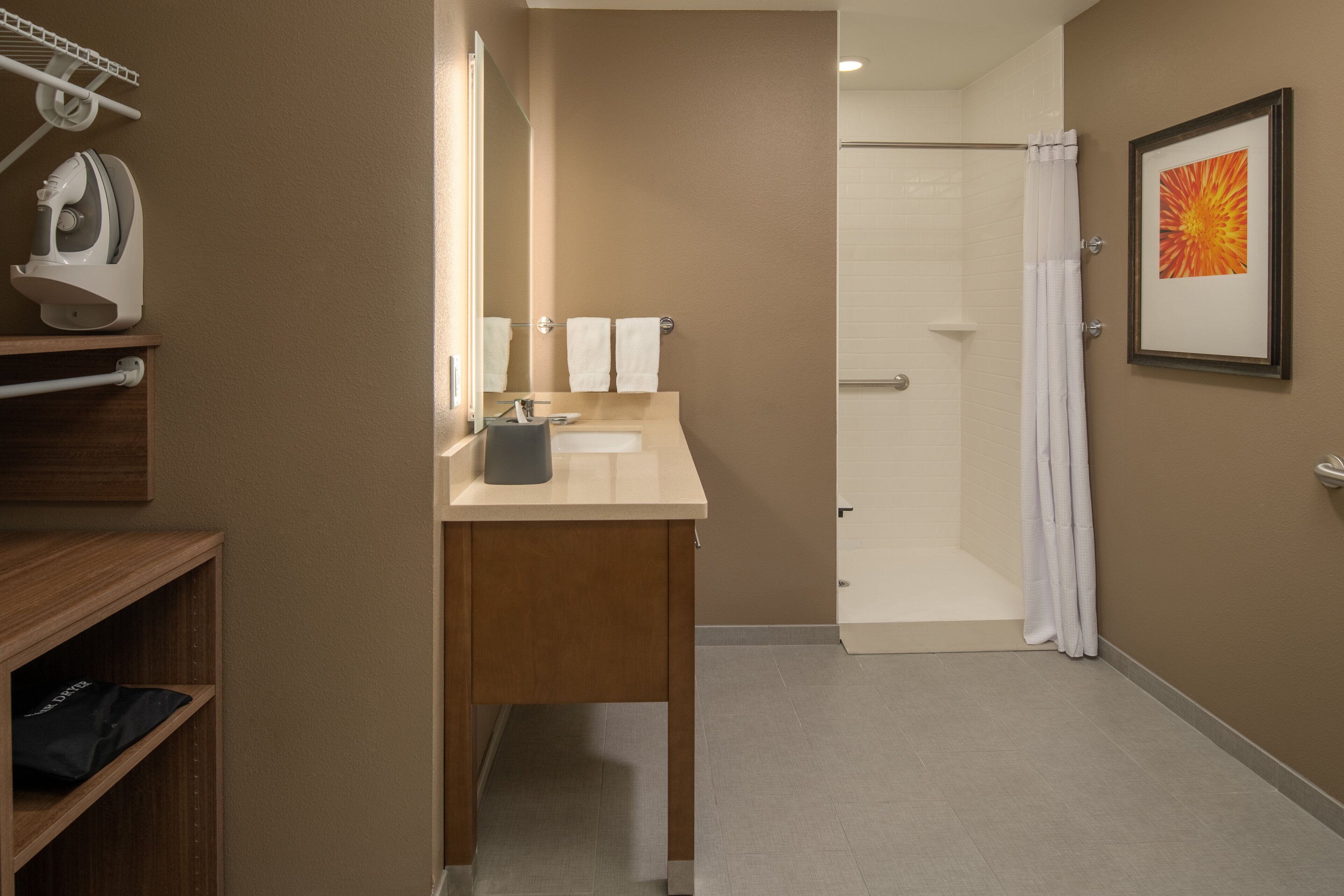 Un baño con tocador de madera, un espejo, un lavabo y una zona de ducha.