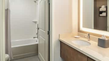 A bathroom with a bathtub, toilet, sink, and a mirror.