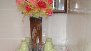 A small kitchen area with a refrigerator, a microwave, and a vase with flowers on top. - Philippine Hostel (Kowloon)