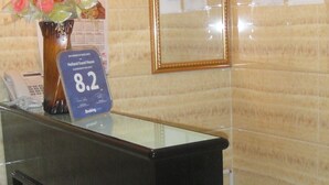 A hotel reception desk with a clock, a flower arrangement, and a sign indicating a 8.2 rating. - Philippine Hostel (Kowloon)