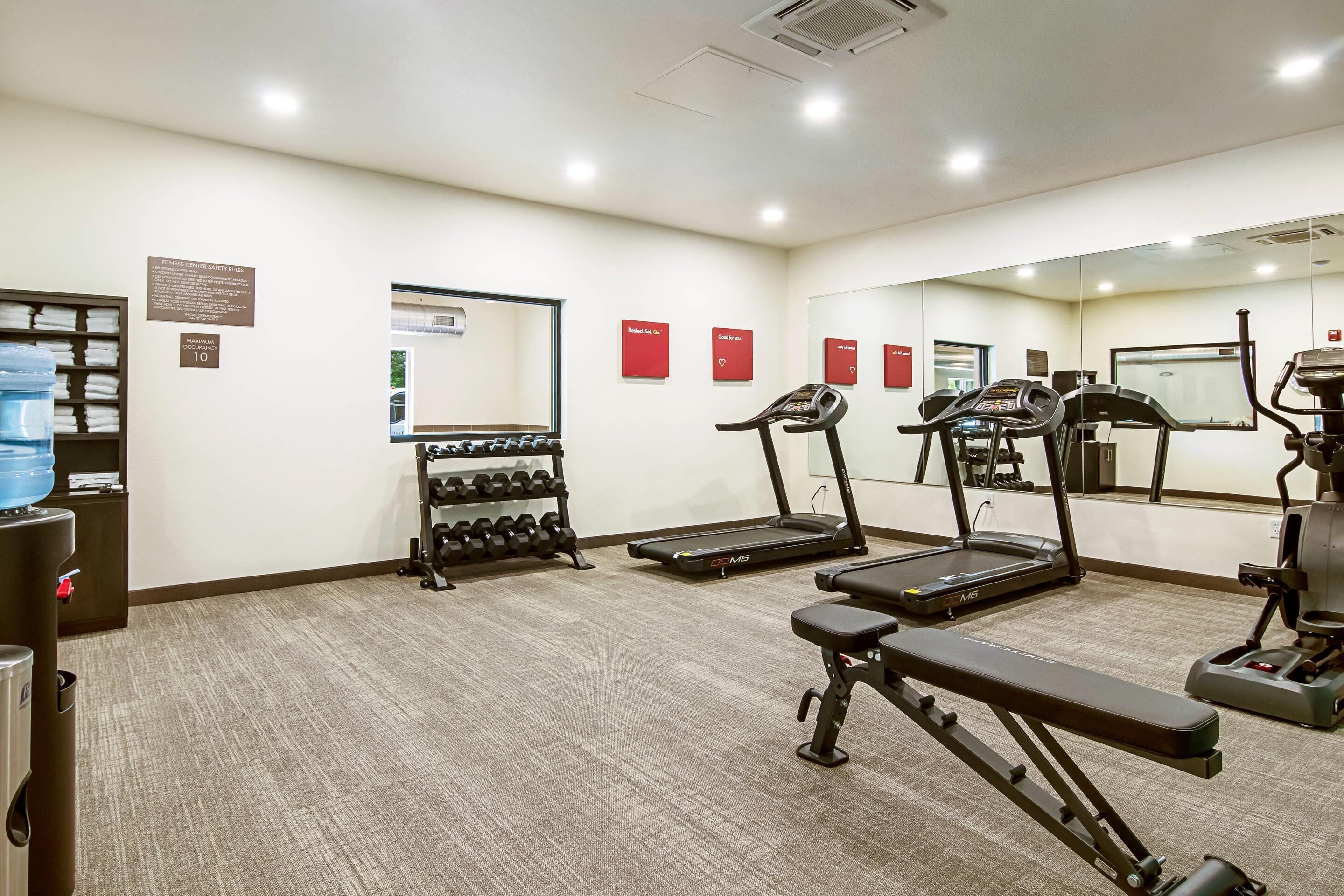 A gym with treadmills, a bench, and a water dispenser.