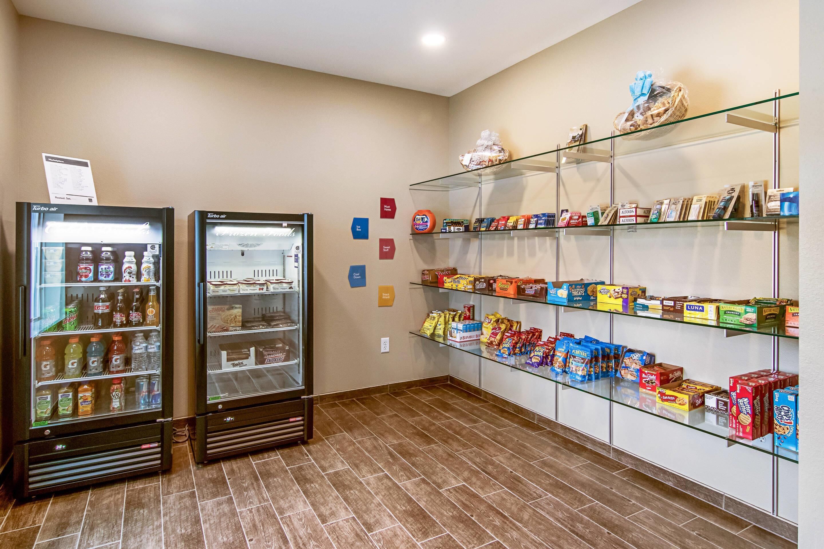 A vending area with two refrigerated drink machines and shelves stocked with snacks and boxed items.