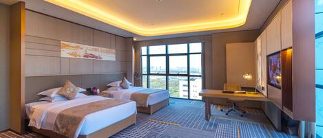 A hotel room with two beds, a desk, and a large window with a city view.