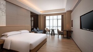 Une chambre d’hôtel moderne équipée d’un grand lit, d’un bureau, de deux chaises et d’une télévision.