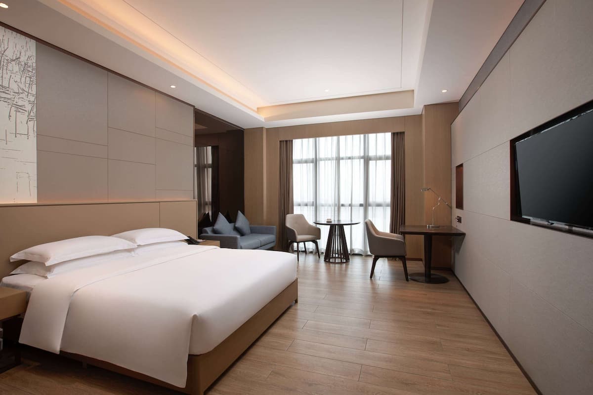 Een moderne hotelkamer met een groot bed, een bureau, twee stoelen en een televisie.
