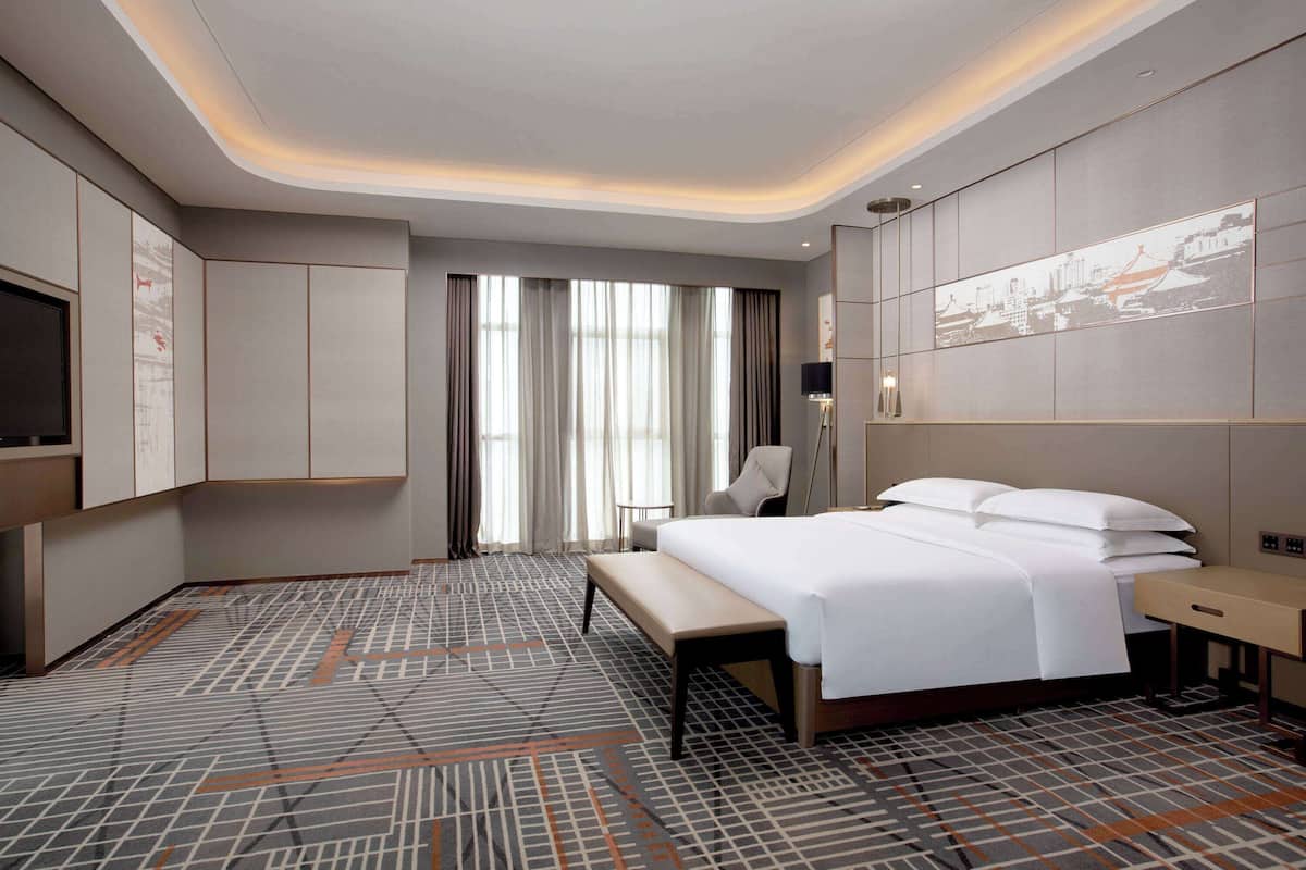 Een moderne hotelkamer met een groot bed, een bureau, een stoel en een televisie.
