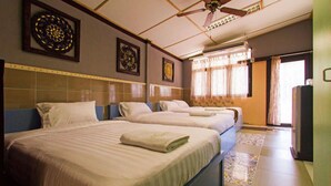 Quarto de hotel com duas camas, um ventilador de teto e janela com cortinas.