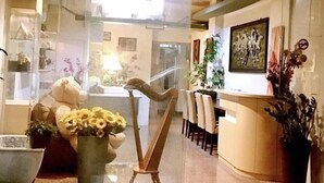 A reception area with a desk, chairs, a large teddy bear, and a harp. - Star B&B (Tainan)
