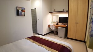 A hotel room with a bed, a desk, a chair, a television, and a wardrobe. - Tainan Yi Zhan (Tainan)