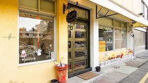 A storefront with a yellow facade, a glass door entrance, and a small awning. - Tainan Yi Zhan (Tainan)