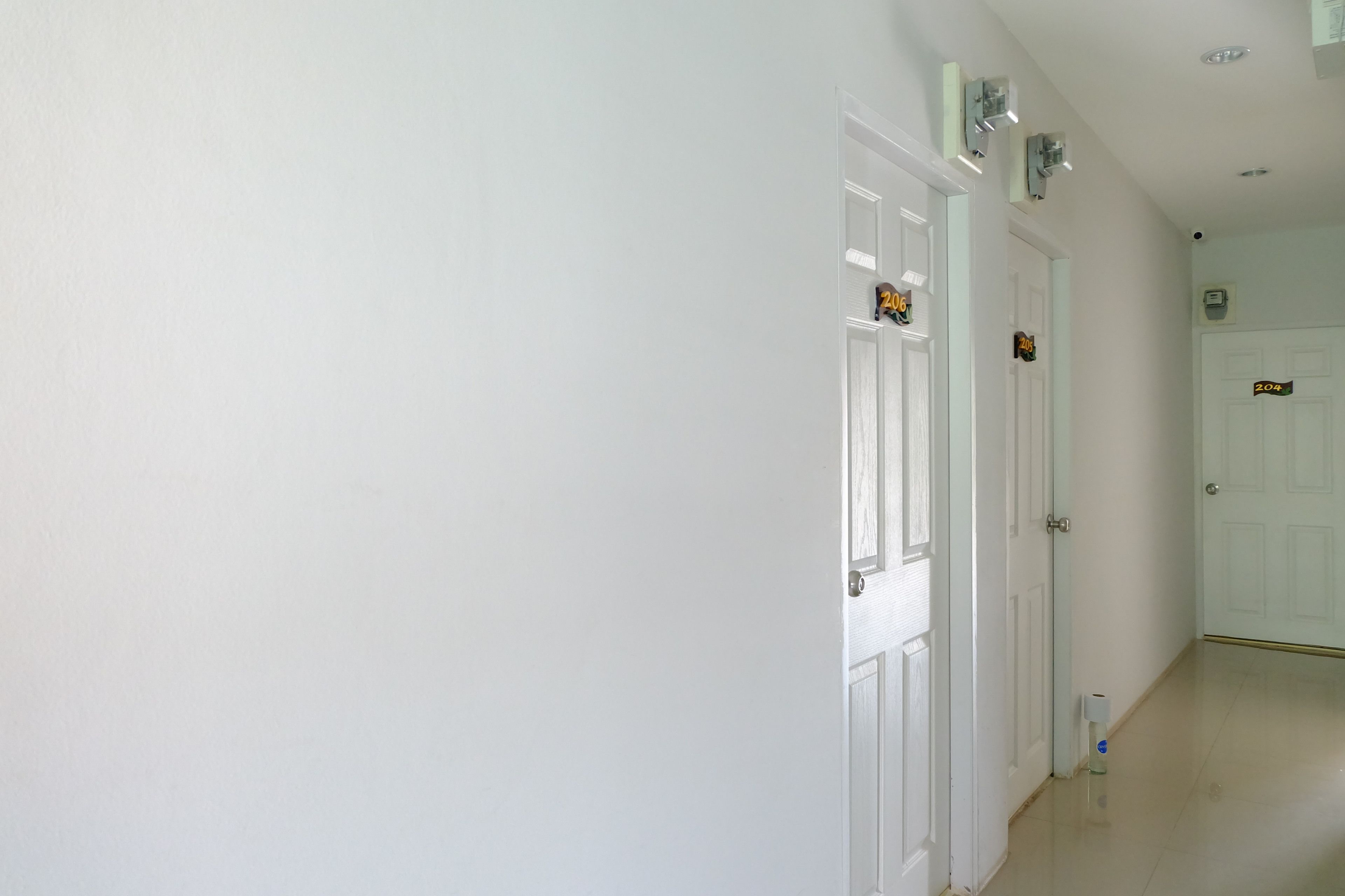 A hallway with white walls and doors, each marked with a number.