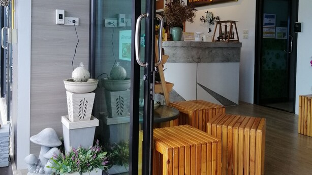 Una zona de recepción moderna con puerta de vidrio, bancos de madera y un mostrador de recepción.