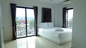 Un dormitorio moderno con una cama grande, vistas de la ciudad a través de ventanas del suelo al techo y un balcón.