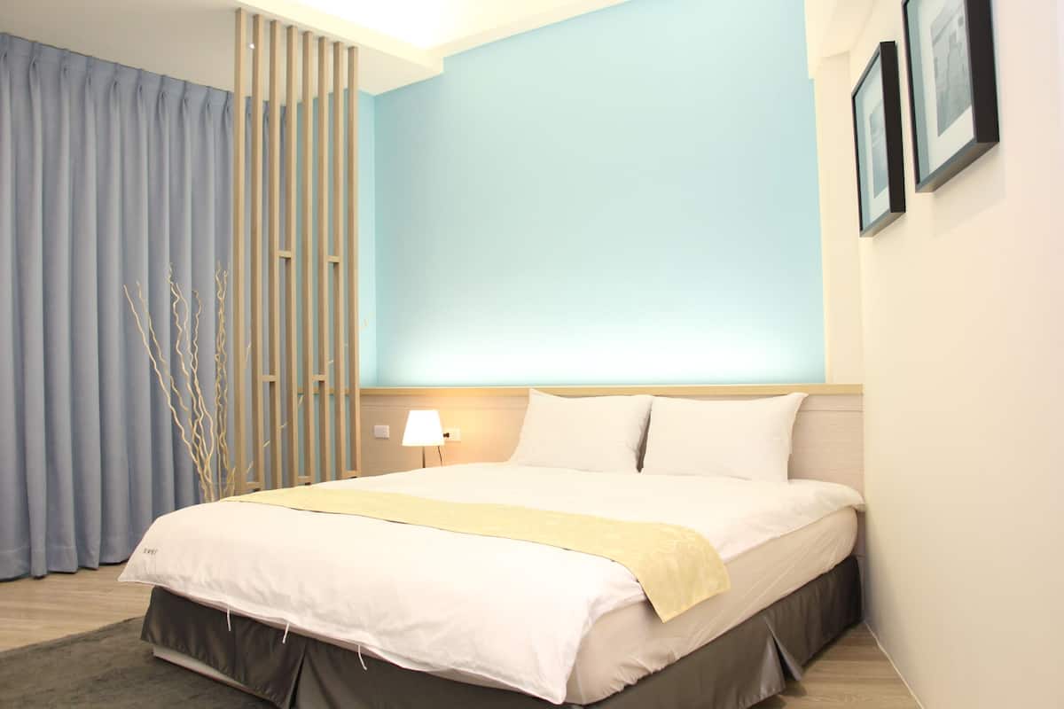 A neatly made bed with a white and yellow bedspread, a wooden headboard, and a nightstand with a lamp.