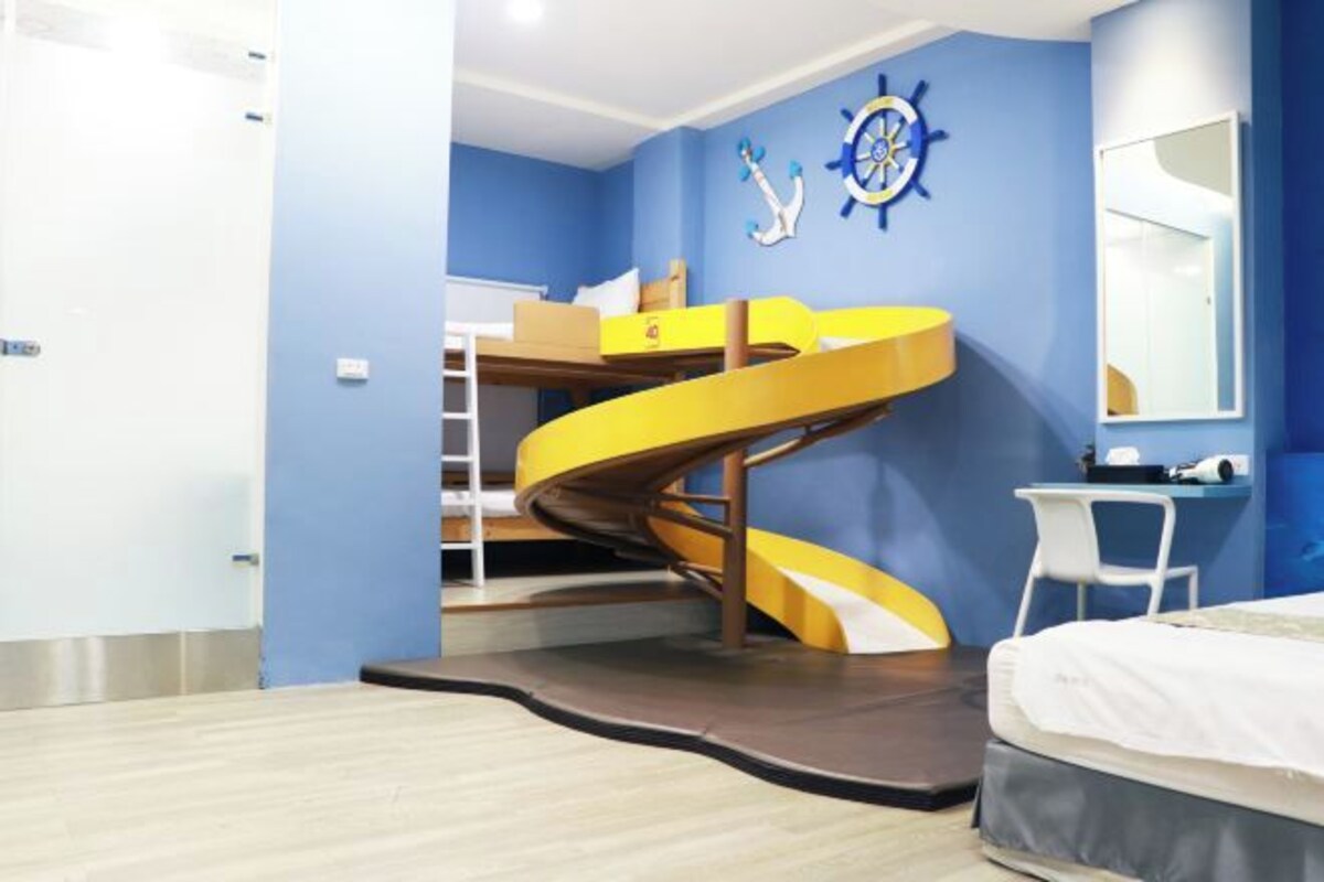 A room with a bunk bed, a spiral staircase, a desk, and a mirror.
