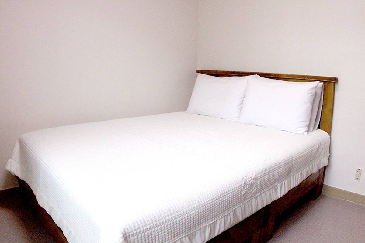 A single bed with a wooden headboard in a room with plain white walls.