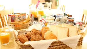 Ein reichhaltiges Frühstücksbuffet mit Brot, Gebäck, Müsli und Saft.