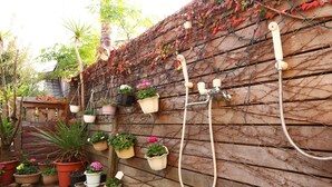 Eine Holzwand mit Blumentöpfen und einem Gartenschlauch.