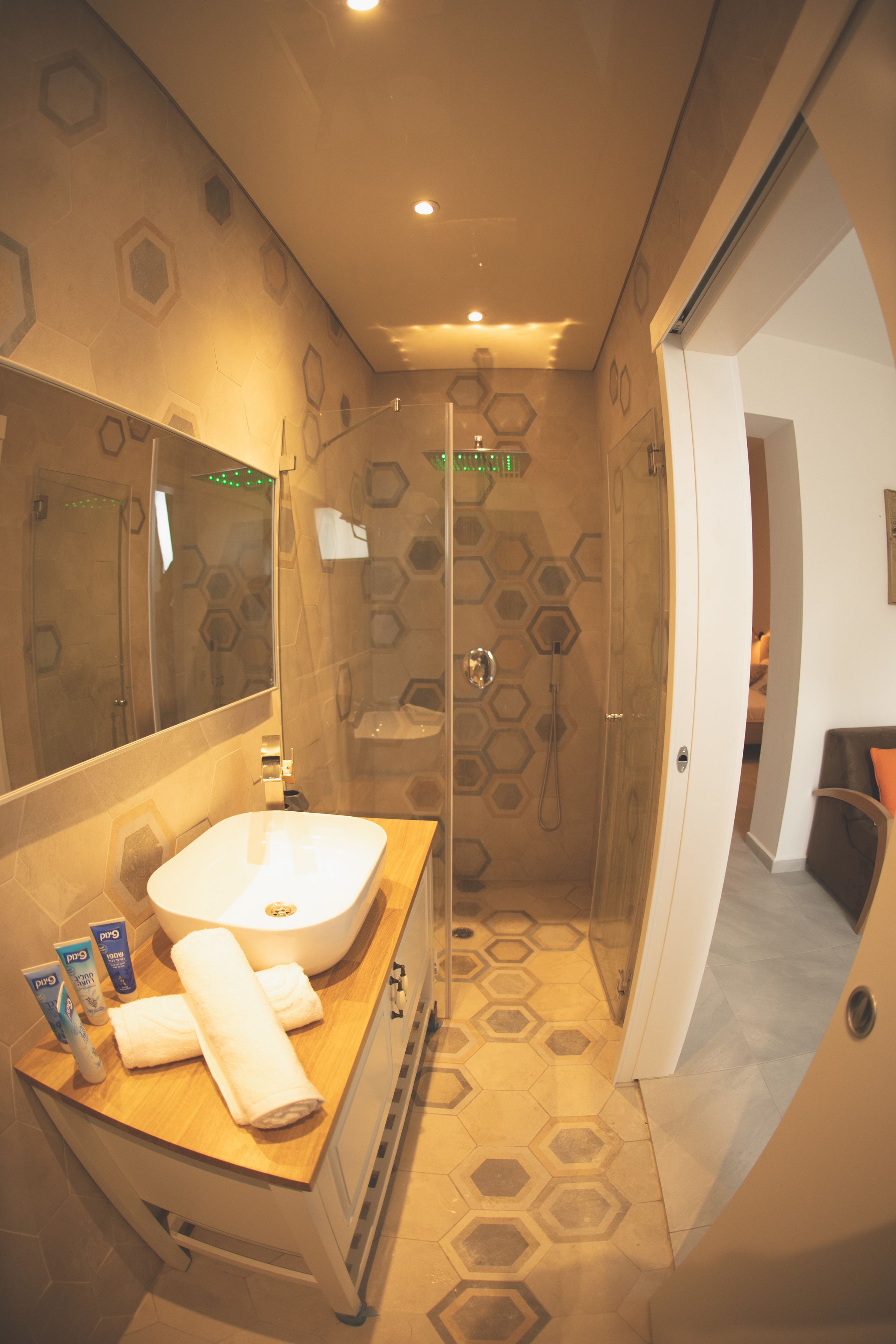 Une salle de bain moderne avec une douche à parois de verre, un meuble-lavabo en bois et un grand miroir.