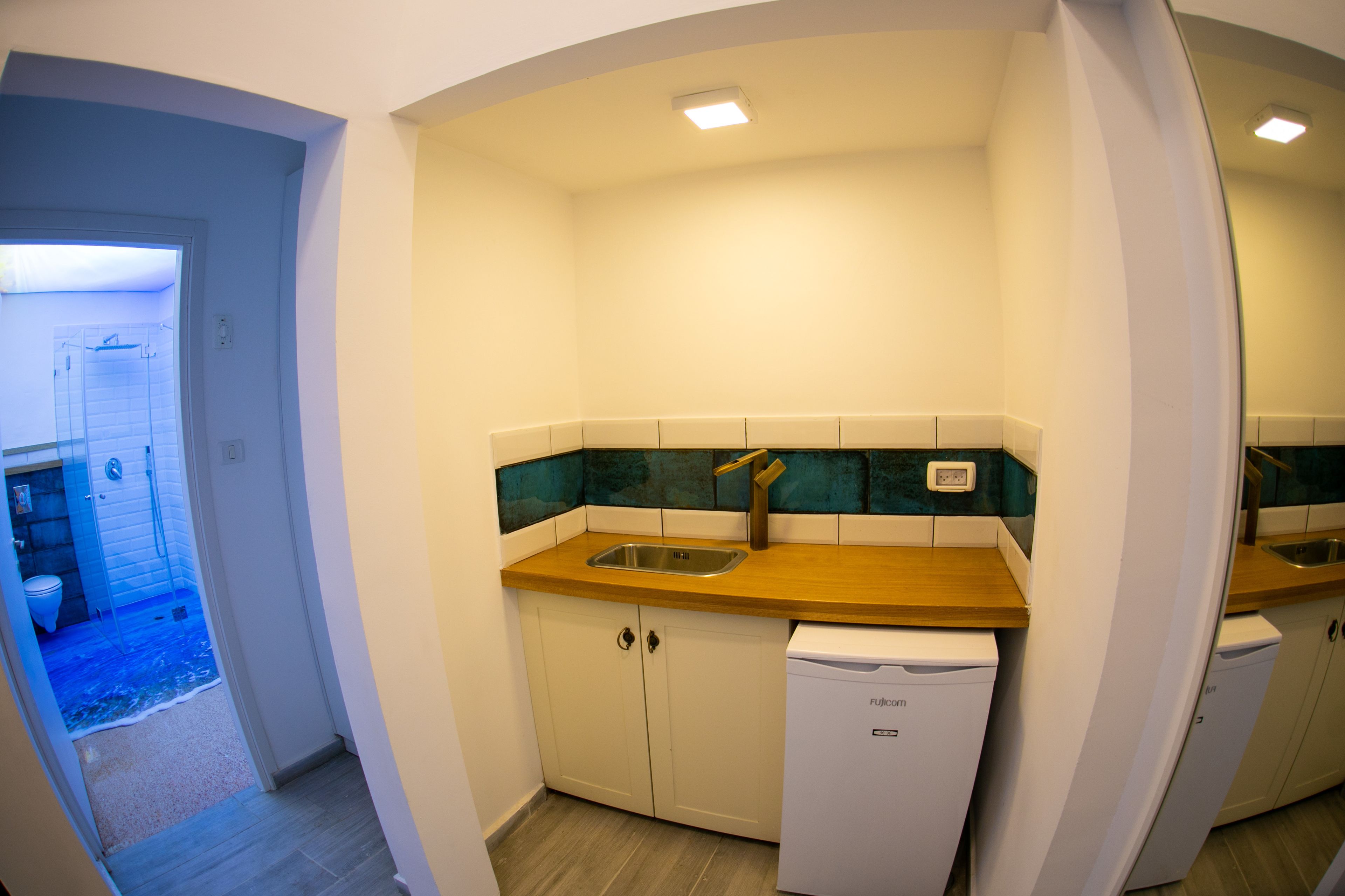A compact kitchen with a wooden countertop, a sink, and two white dishwashers.