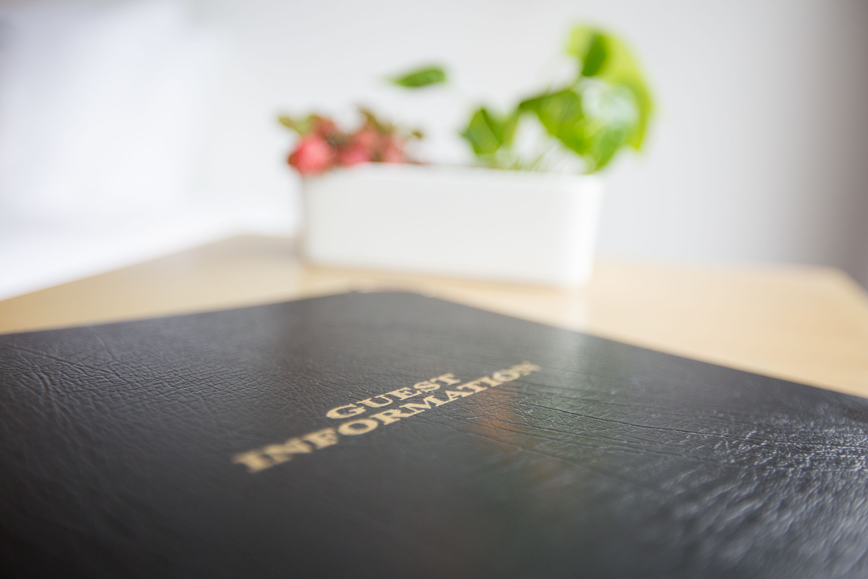 A black leather-bound book titled "GUEST INFORMATION" on a wooden surface.