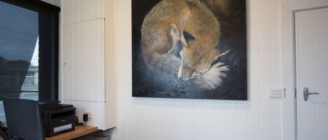 A reception desk with a computer, printer, and a painting of a fox on the wall.