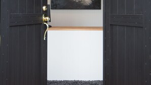 Een donkerhouten deur met ruitpanelen, een aan de muur bevestigd schilderij van een vos, en een betegelde vloer.