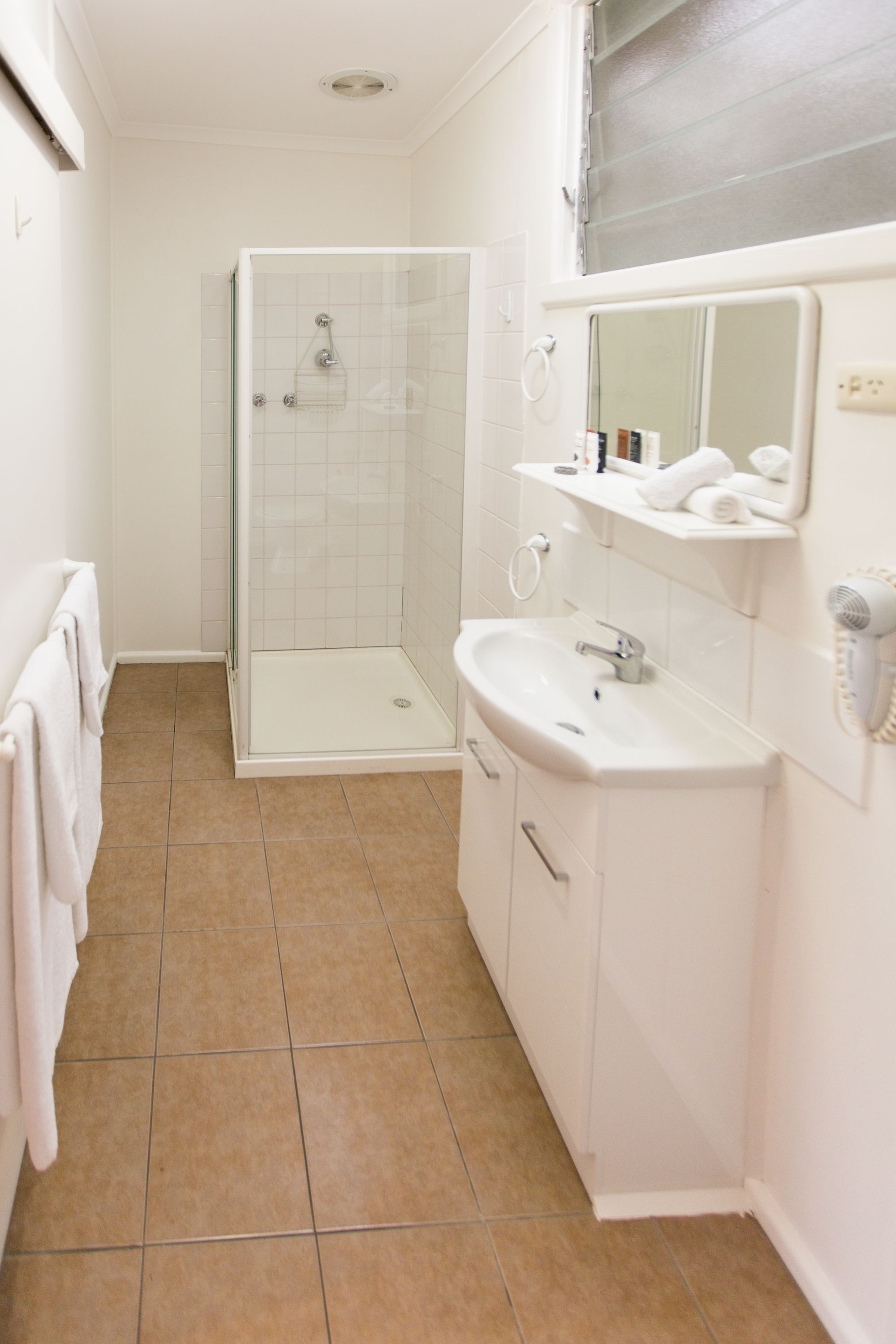 A bathroom with a glass shower enclosure, a sink, and a mirror.