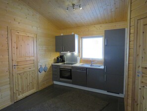 Una cucina compatta con pareti in legno, una finestra ed elettrodomestici essenziali.
