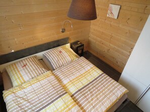 Una camera in legno con un letto, un comodino e una lampada.