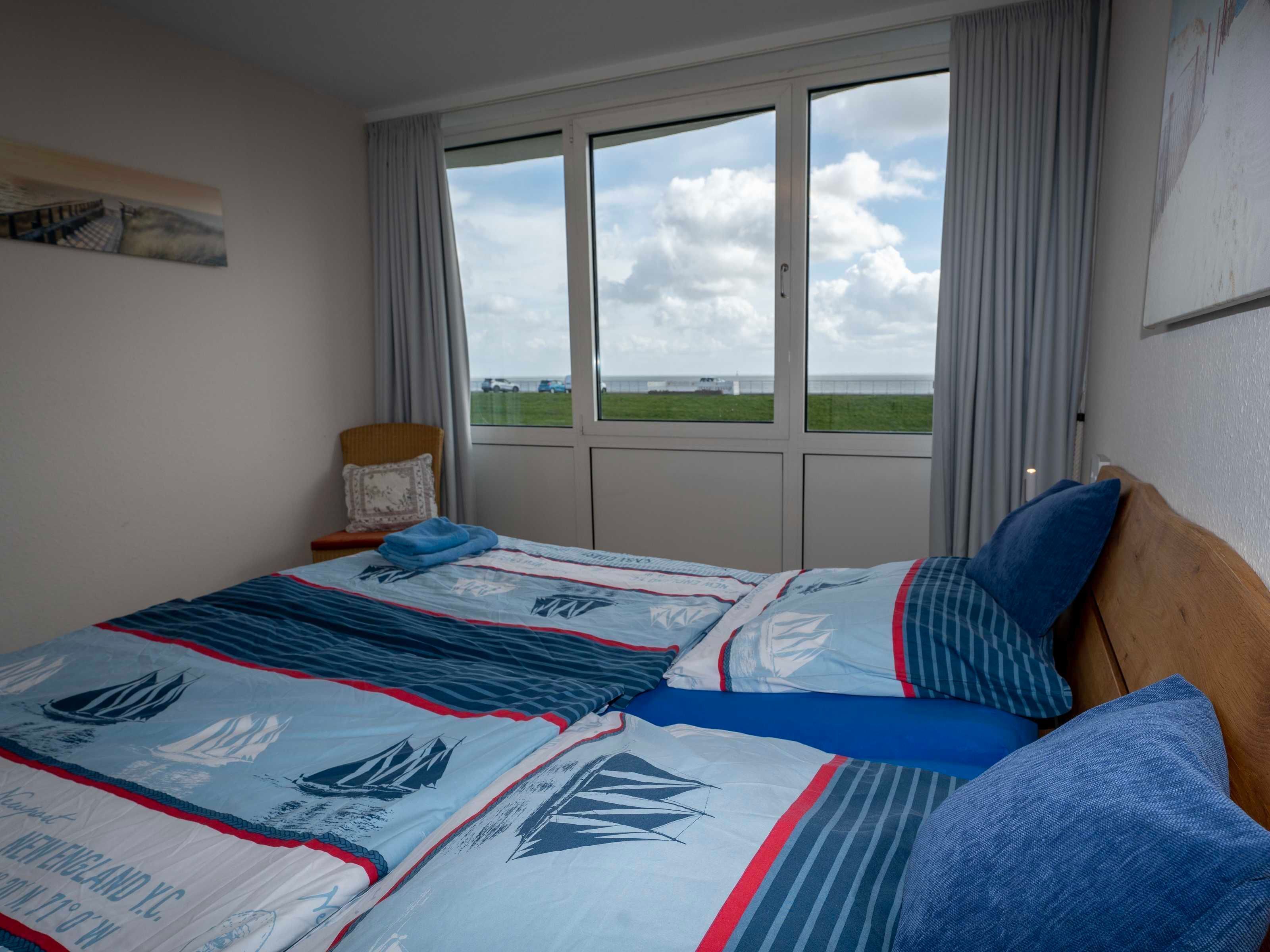 Ein Schlafzimmer mit einem großen Bett, einem Sessel, einem Fenster mit Blick auf die Landschaft und einem Bild an der Wand.