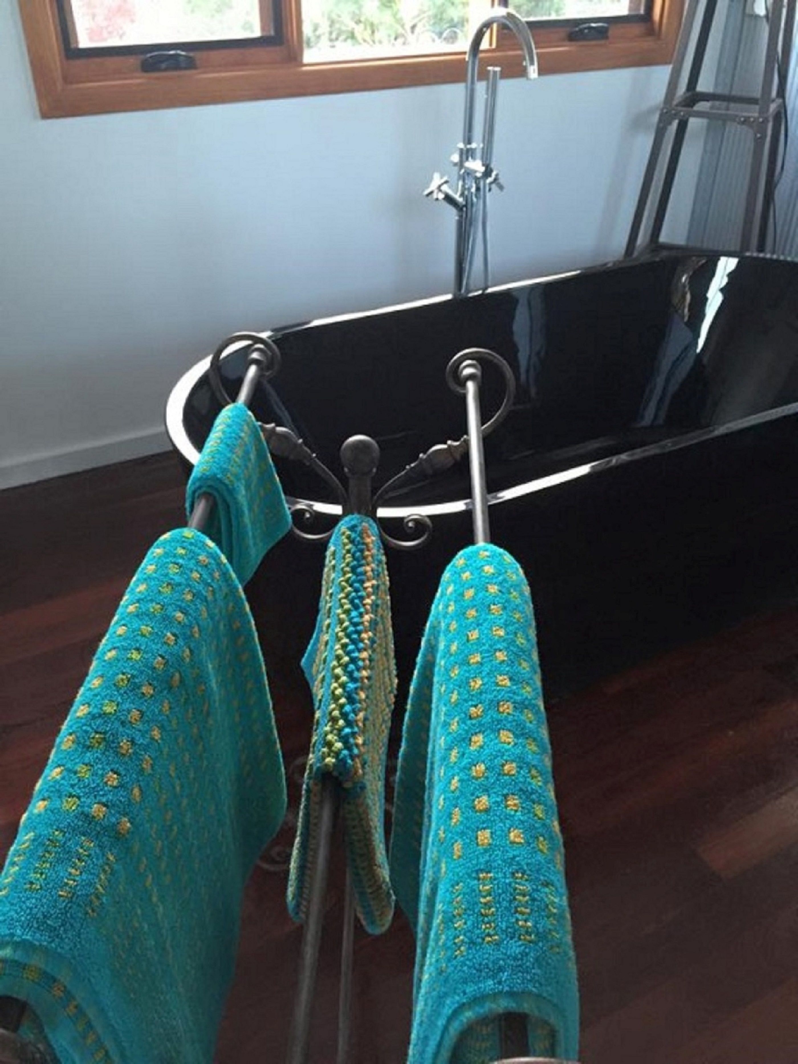 A bathtub with a chrome faucet and a towel rack with three towels.