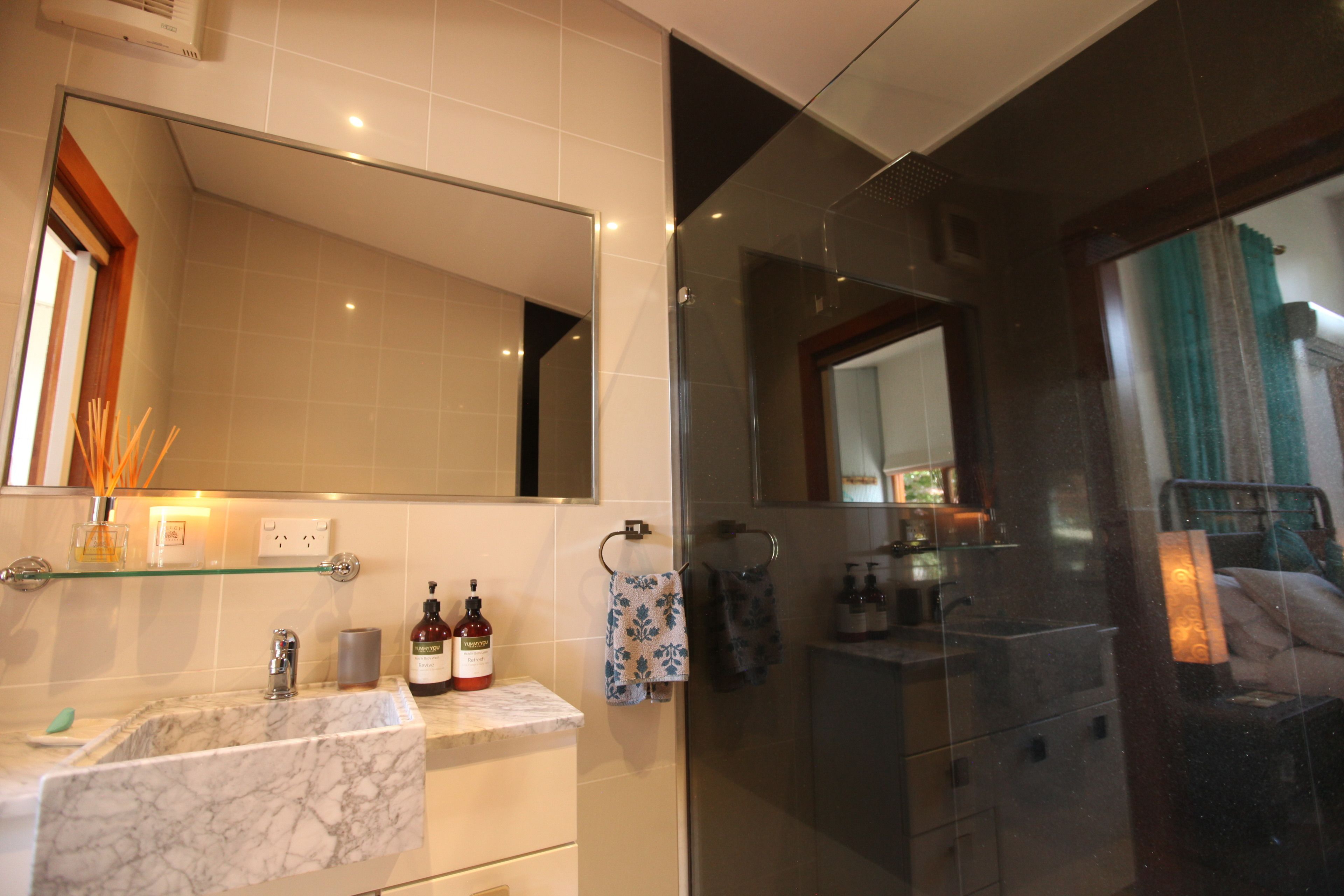 A modern bathroom with a marble sink, a glass shower enclosure, and a large mirror.